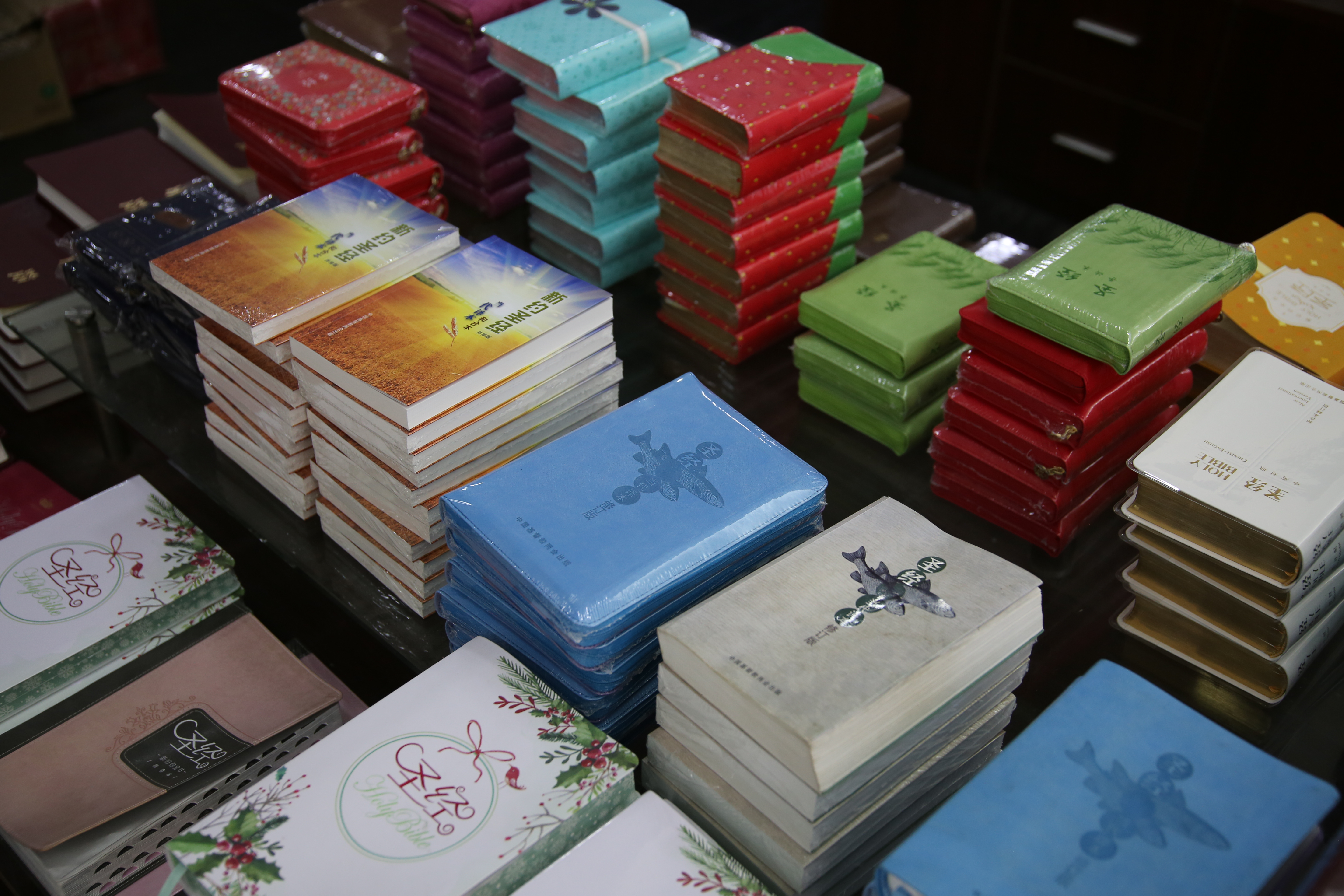 Erivärisiä, eri painoasuisia kiinankielisiä Raamattuja pinoissa.