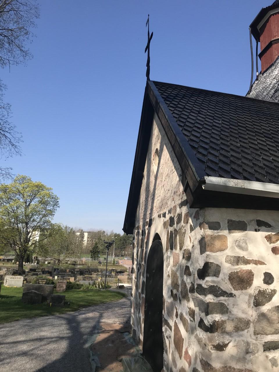 Kirkon ovi risti katolla kirkkaan sininen taivas taustalla hautausmaa
