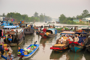 Kelluvat markkinat. Vihannekset ja hedelmät myydään joella olevista isoista ja pienistä veneistä. Veneet ovat kirkkaan sinisiä ja punaisia. Osassa on pieni katos, isommissa kajuutta. Paikkana on Thaimaa.